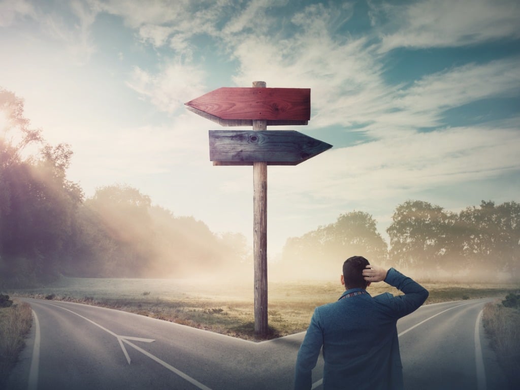 rear-businessman-in-front-of-crossroad-and-signpost-arrows